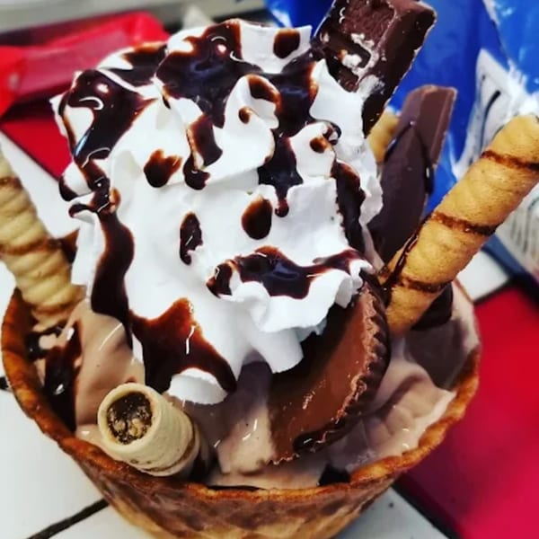 Chocolate ice cream sundae in a waffle bowl, topped with whipped cream, chocolate syrup, and candies.