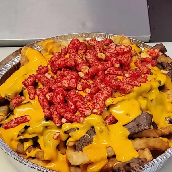 Sno-White Drive In's loaded fries with melted cheese, steak, and spicy red crunchy toppings.